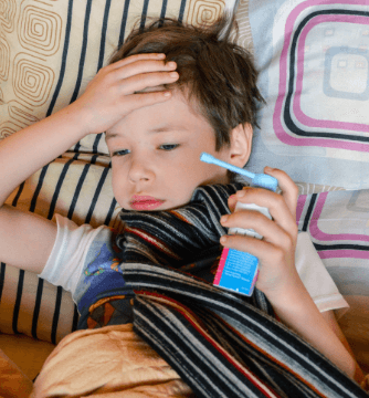 A Boy Child has Asthma and holding his head and inhaler 