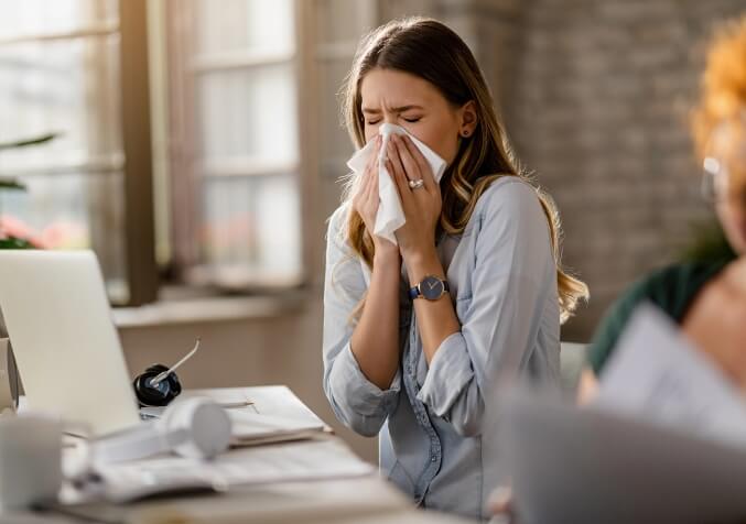 Woman Sneezing in front of laptop