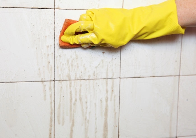 Gloved Hand Cleaning a Dirty Tiled Wall